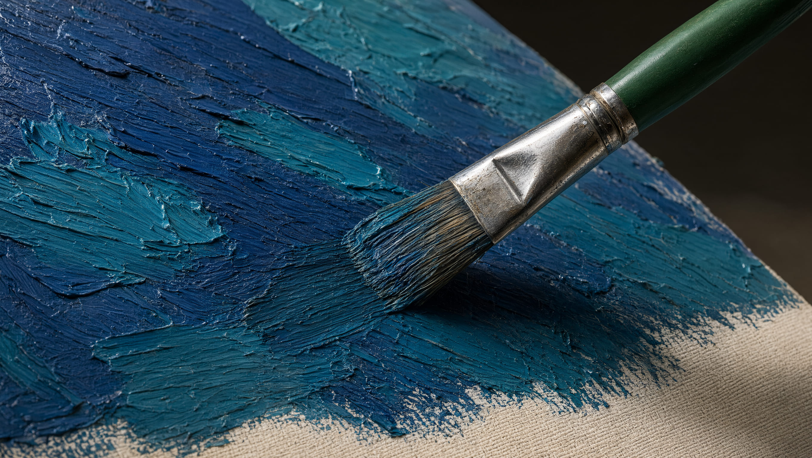 Paintbrush applying thick blue paint across a textured canvas.